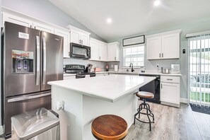 A modern kitchen with stainless steel appliances, white cabinetry, and a large island with stools. - Arcade Games, Lanai & Spa: Summerfield Family Home (Summerfield)