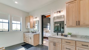 Un baño moderno con un espejo grande, armarios de madera y una encimera de mármol.