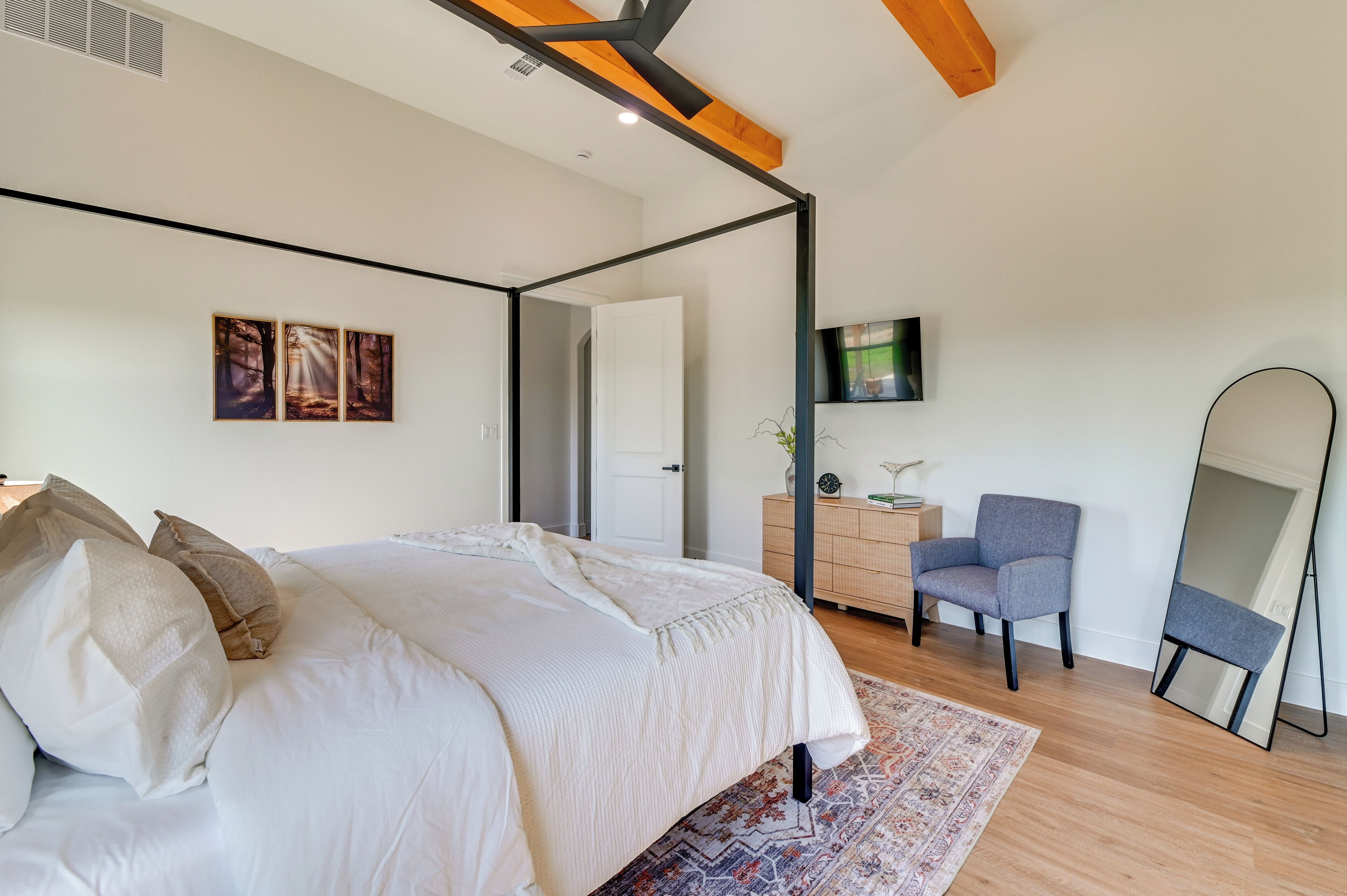 Een slaapkamer met een hemelbed, een kaptafel, een stoel, een televisie en een spiegel.