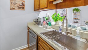 Una cocina con armarios de madera, un lavamanos de acero inoxidable, una barra de café y un letrero en la pared.