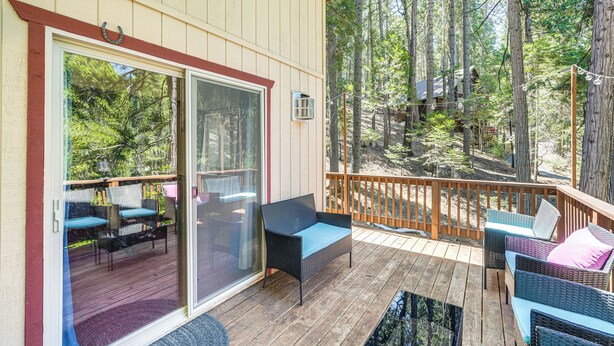 A covered deck with wicker furniture and a glass door leading to a patio area.