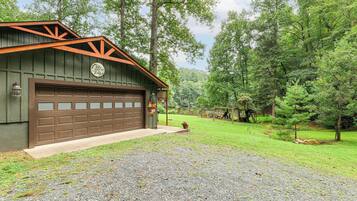 A rustic cabin with a garage, surrounded by a well-maintained lawn and trees.