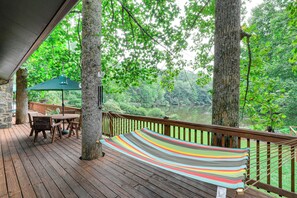 A wooden deck with a hammock, a table, and chairs, overlooking a forested area. - Deck & Game Room! Lakefront Blue Ridge Mtn Gem (Deep Gap)