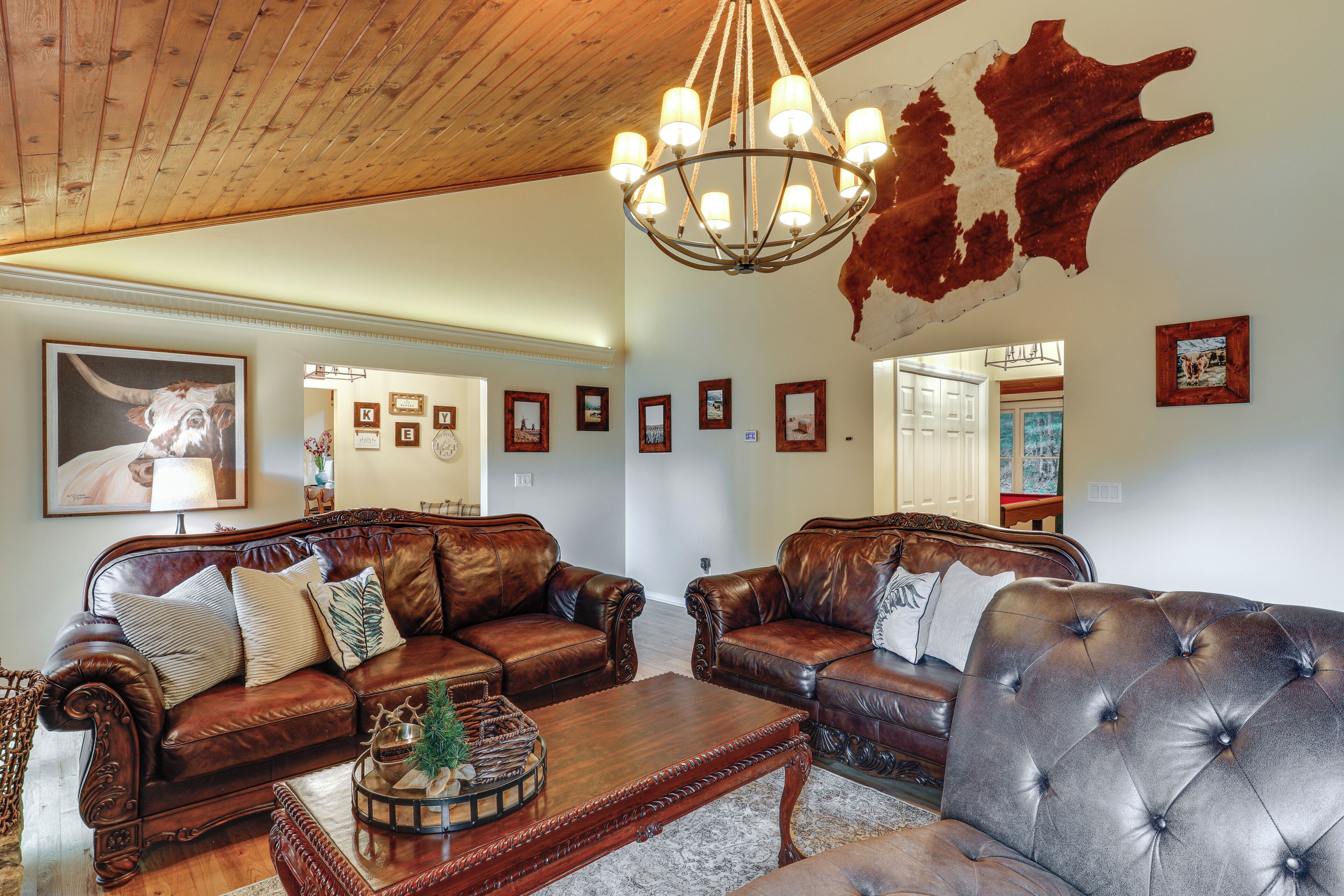 A spacious living room with leather sofas, a wooden coffee table, and a chandelier.