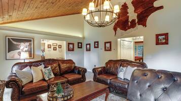 A spacious living room with leather sofas, a wooden coffee table, and a chandelier.