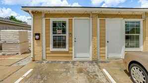 A beige building with two white doors and windows, a parking lot, and a beige car parked in front. - Suburban Home By Arthur Storey Park & HCA Houston! (Houston)