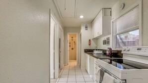 A kitchen with white cabinets, a stove, and a window with blinds. - Suburban Home By Arthur Storey Park & HCA Houston! (Houston)