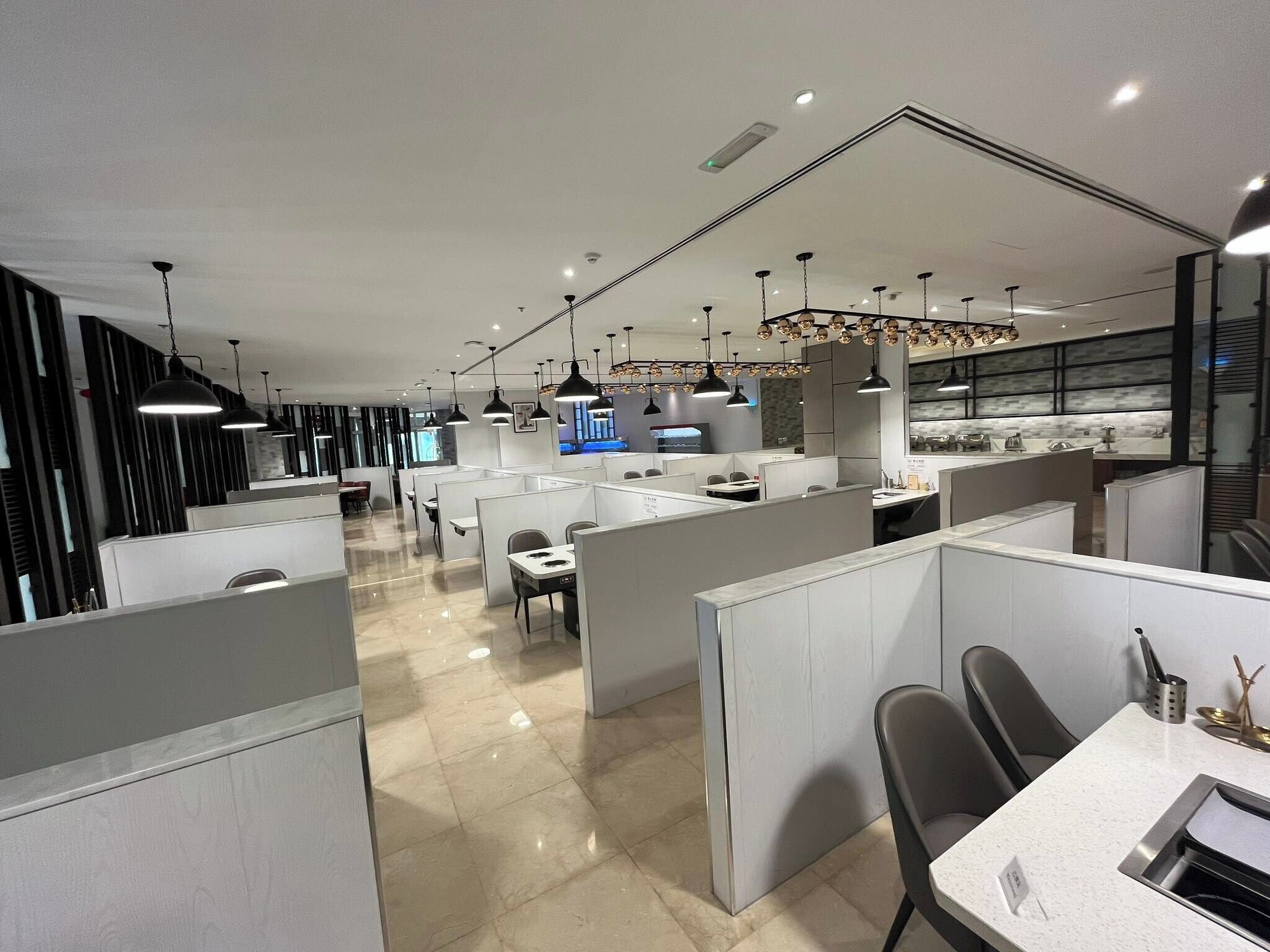 A modern office space with cubicles, desks, and a central area with a counter and seating.