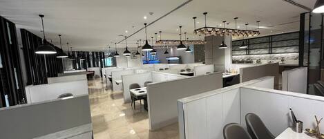 A modern office space with cubicles, desks, and a central area with a counter and seating.