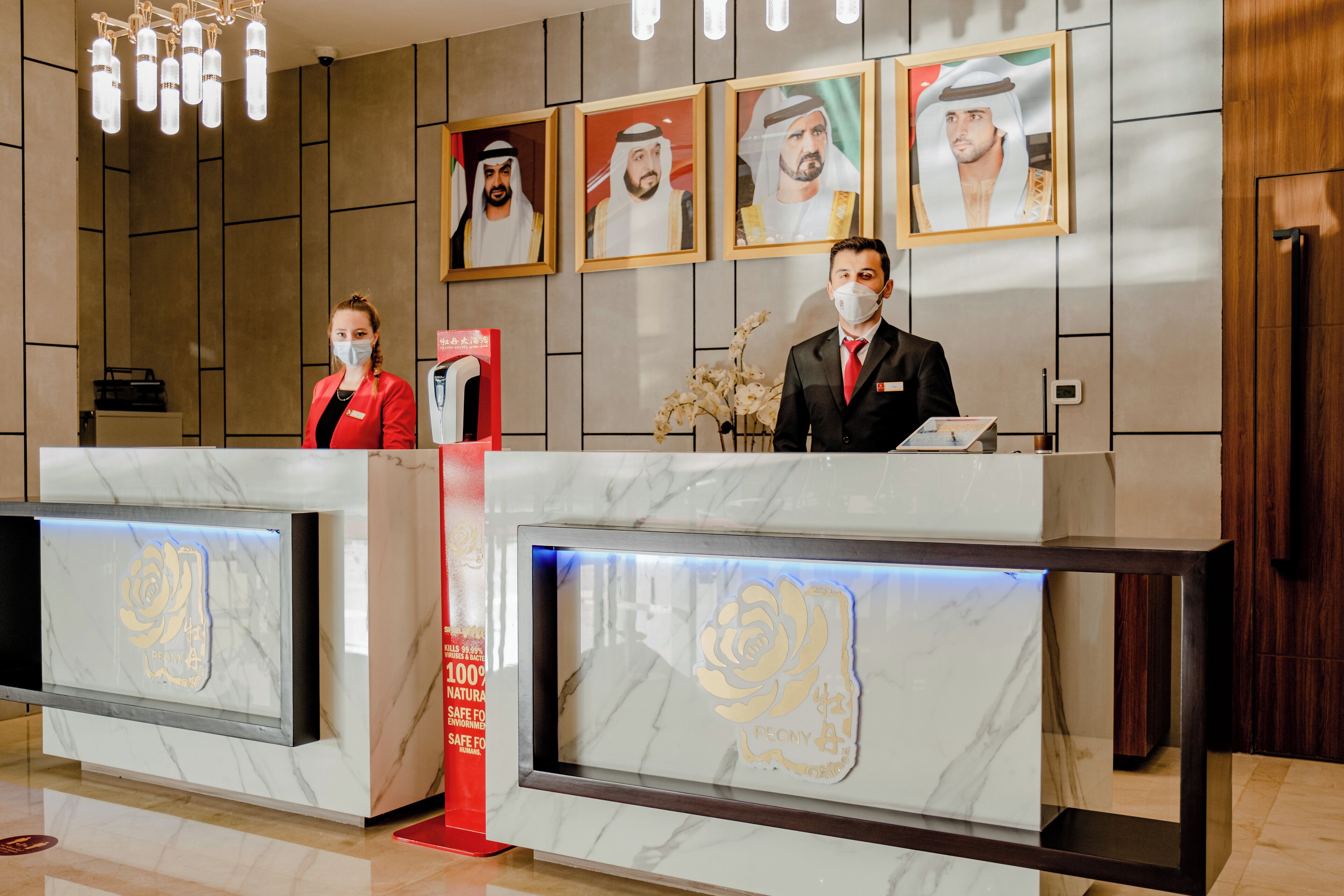 A hotel reception desk with marble surfaces and framed portraits on the wall.