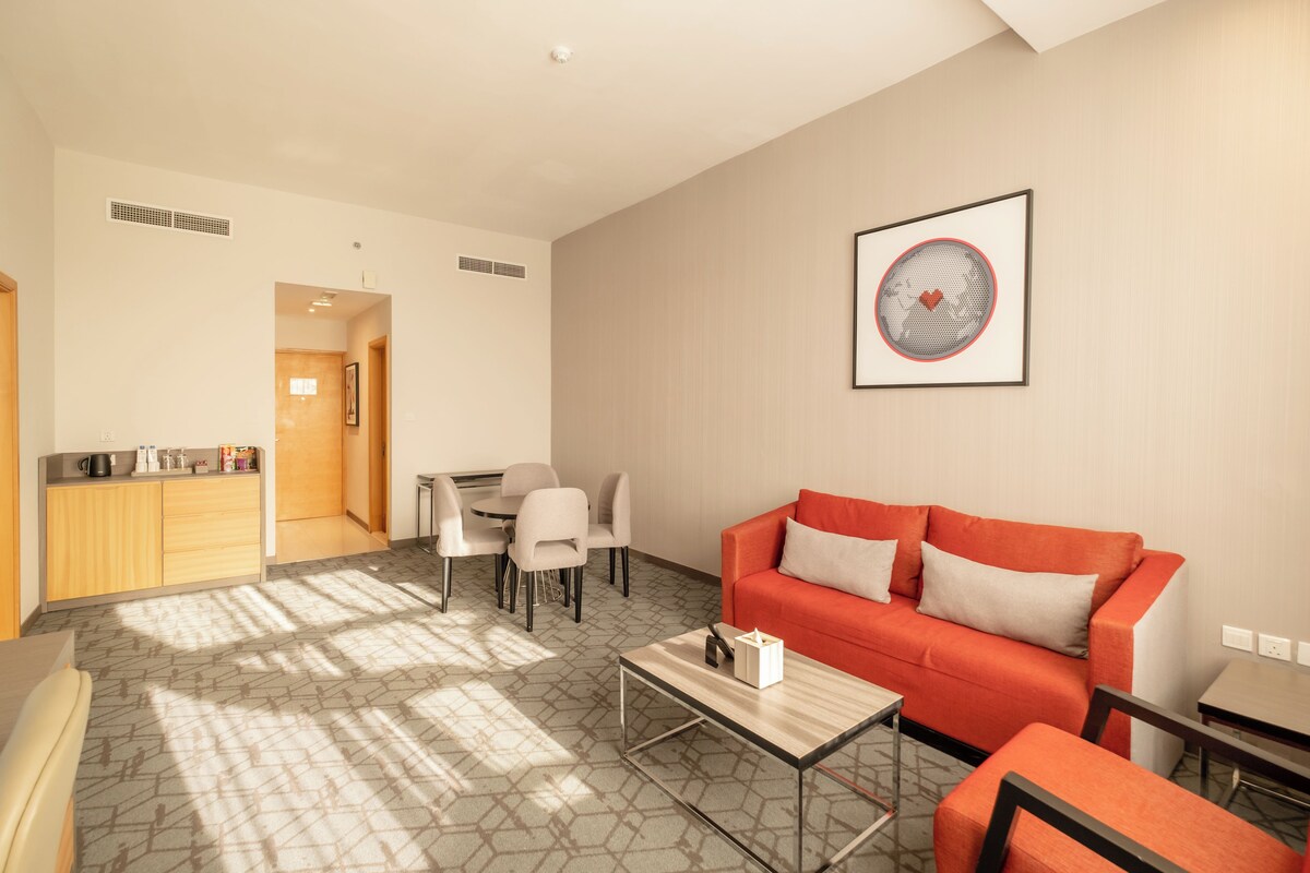 A modern living room with a red sofa, a coffee table, and a dining area with chairs and a table.