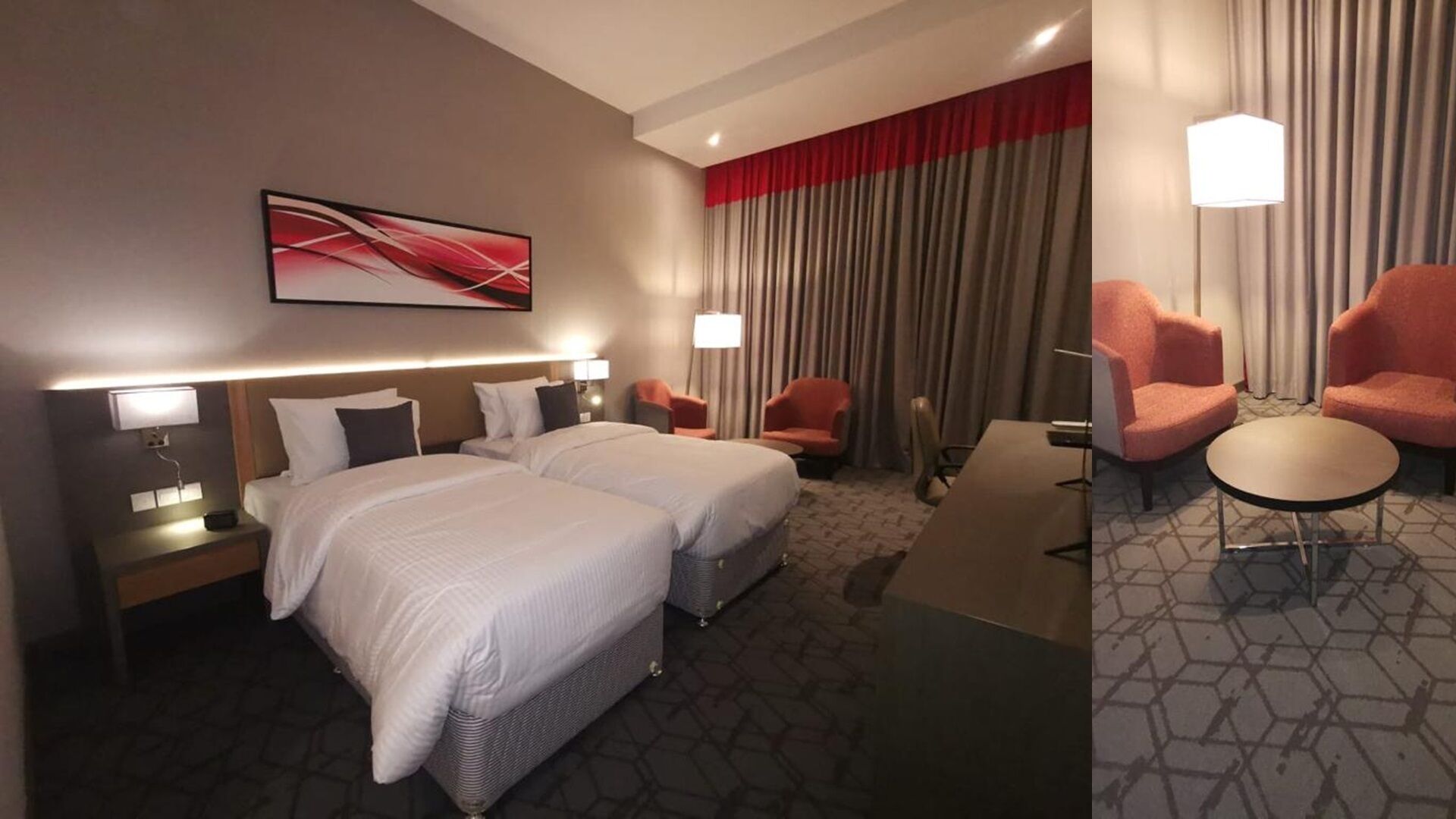 A hotel room with two beds, a desk, two armchairs, and a large window with curtains.