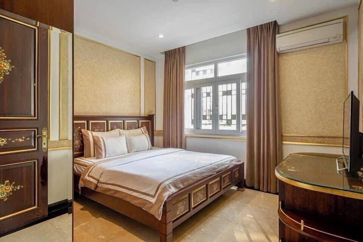 Ein Hotelzimmer mit einem großen Bett, einem Holzschrank, einem Glastisch und einem Fenster mit Vorhängen.