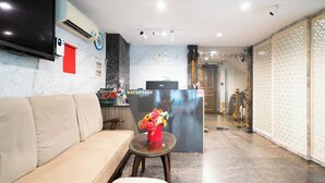 A reception area with a sofa, a table with a vase of flowers, a clock, and a reception desk. - Nicecy Hotel & Apartment - Central Sai Gon (Ho Chi Minh City)
