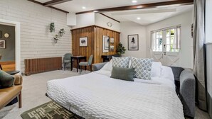 A bedroom with a large bed, a wooden cabinet, a desk with a chair, and a radiator. - Noble Crest! Apartment w/ Poker Table & Hot Tub (Colorado Springs)