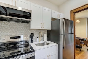 A modern kitchen with white cabinets, a stainless steel refrigerator, and a built-in oven.
