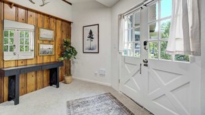 A hallway with a wooden bench, a white door, and a window with curtains. - Noble Crest! Apartment w/ Poker Table & Hot Tub (Colorado Springs)
