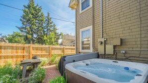 A backyard with a hot tub, a wooden table, and a brick pathway. - Noble Crest! Apartment w/ Poker Table & Hot Tub (Colorado Springs)