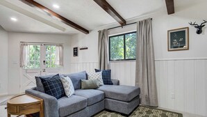 A cozy living room with a grey sectional sofa, a wooden side table, and a patterned rug. - Noble Crest! Apartment w/ Poker Table & Hot Tub (Colorado Springs)