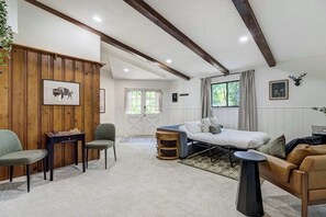 A cozy room with a bed, a sofa, and a desk with a board game.