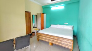 A bedroom with a bed, a desk, a chair, a wardrobe, and a mirror. - Dhanas Residency Pondicherry (Puducherry)