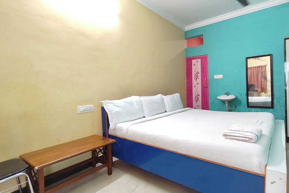 Quarto com cama, mesa de cabeceira, guarda-roupa, pia e espelho.