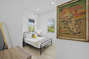 Un dormitorio con cama, dos ventanas, un mapa de Florida en la pared y una mesa de madera.