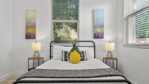 A modern bedroom with a bed, two bedside tables with lamps, and artwork on the walls.