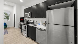 A modern kitchen with dark cabinets, stainless steel appliances, and a built-in microwave.
