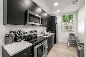 A modern kitchen with black cabinets, stainless steel appliances, and a window with a view of greenery. - Pineapple Paradise #3 • 13 min to Beach • Fire Pit (Sarasota)