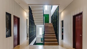 A modern interior with a central staircase, flanked by doors and a decorative wall. - INNCA Simpang Lima, Semarang (Semarang)