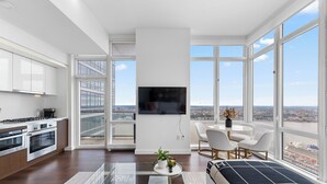 Un appartement moderne doté d’une cuisine, d’un coin repas et d’une grande fenêtre offrant une vue sur la ville.