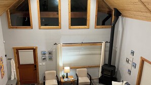 Una sala de estar estilo loft acogedora, con techo alto, ventanas amplias, chimenea y comedor.