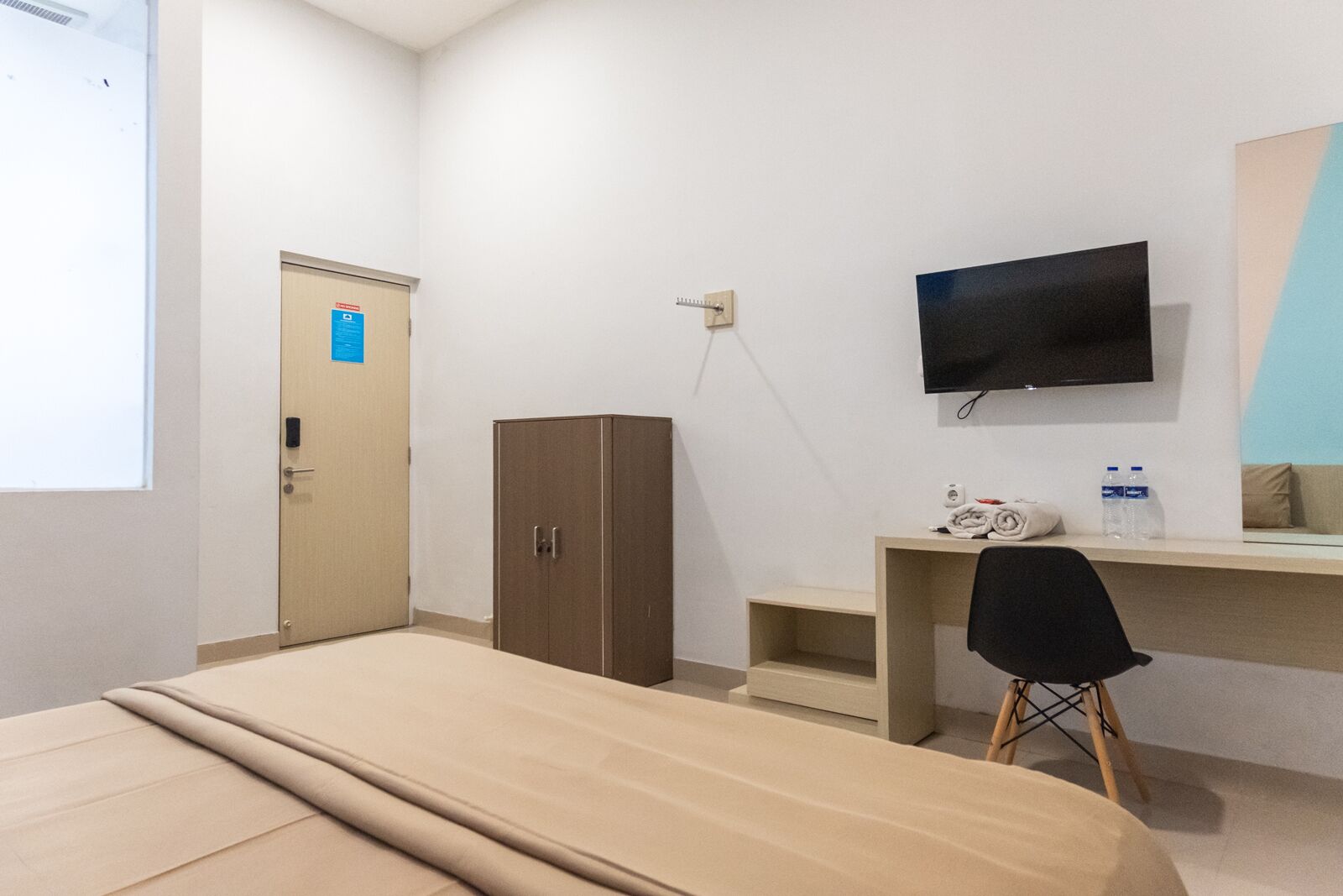 Ein Hotelzimmer mit einem Bett, einem Schreibtisch, einem Fernseher, einem Kleiderschrank und einem Sessel.
