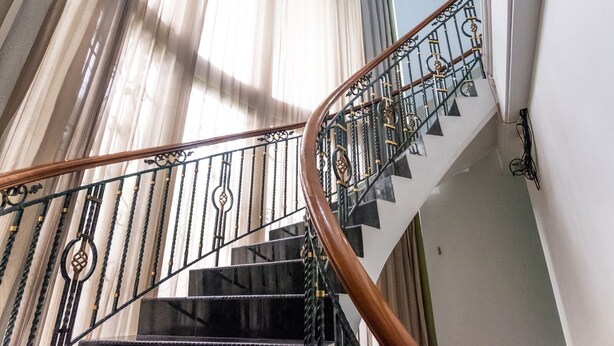 A staircase with ornate metal railings and wooden handrails, leading to an upper floor. - INNCA Telaga Bodas, Semarang (Semarang)