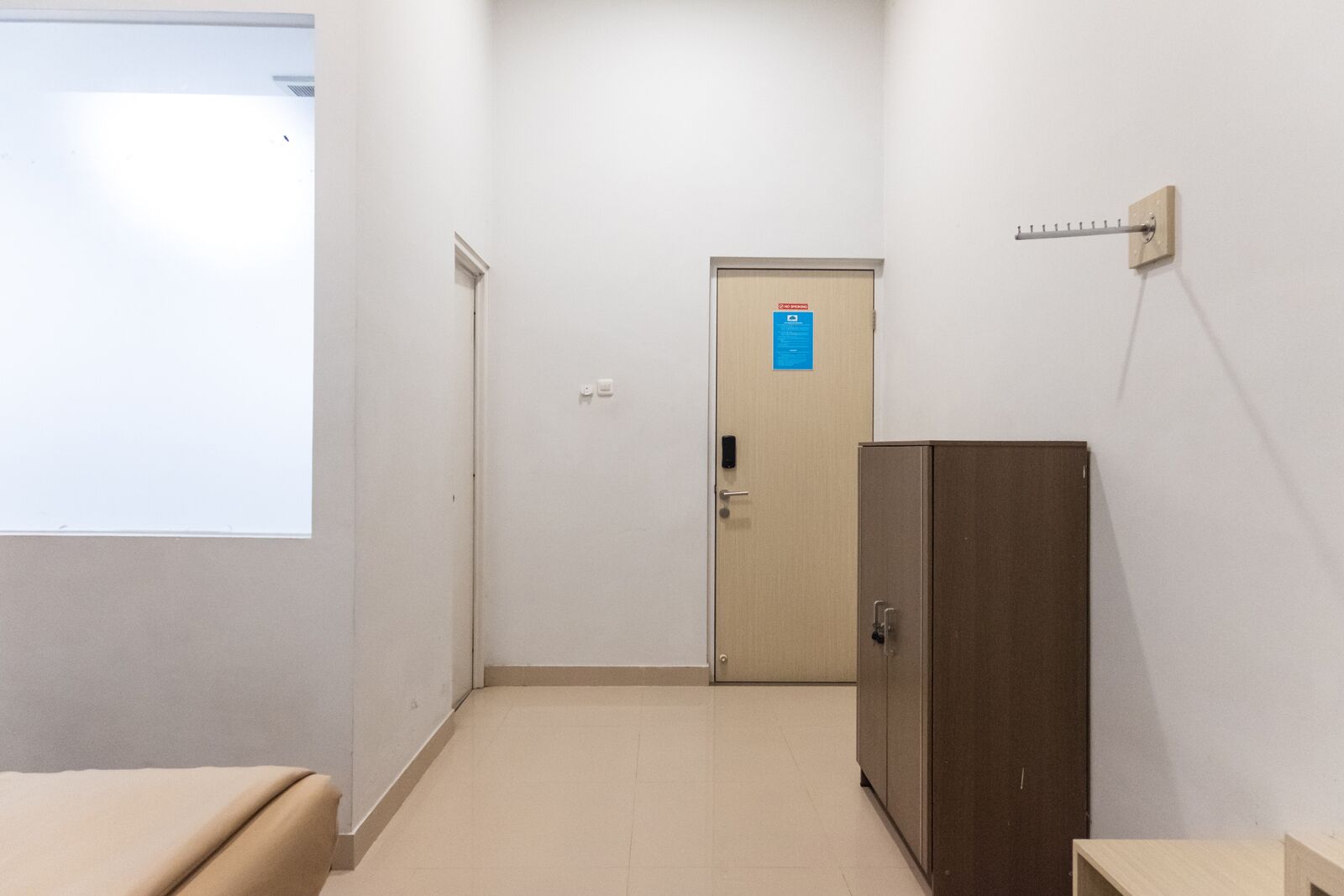A narrow hallway with a door at the end, a small cabinet, and a projector screen on the left wall.