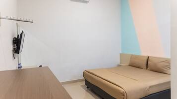 Una habitación pequeña y ordenada con una cama, una mesa y un equipo de aire acondicionado.