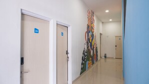 A hallway with two doors labeled 101 and 102, a colorful abstract mural on the wall, and a blue wall on the right. - INNCA Telaga Bodas, Semarang (Semarang)