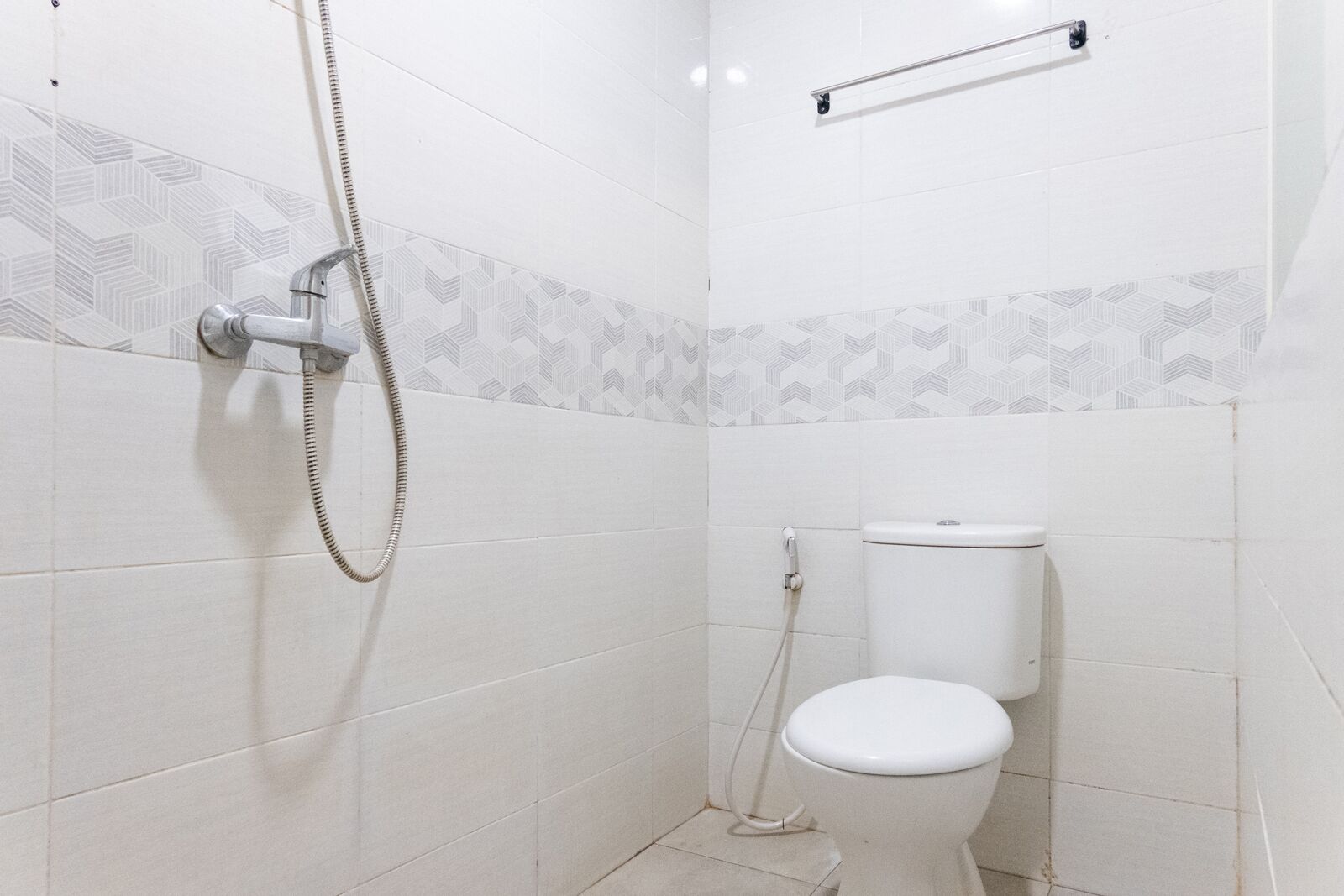 A small, clean bathroom with a toilet, shower, and towel rack.