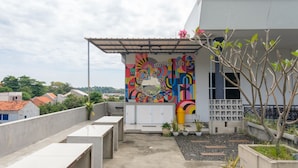 A rooftop terrace with a colorful mural, concrete seating, and potted plants. - INNCA Telaga Bodas, Semarang (Semarang)