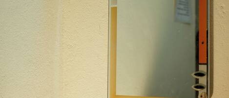 A wall-mounted mirror with a wooden frame and a small sign on the wall.