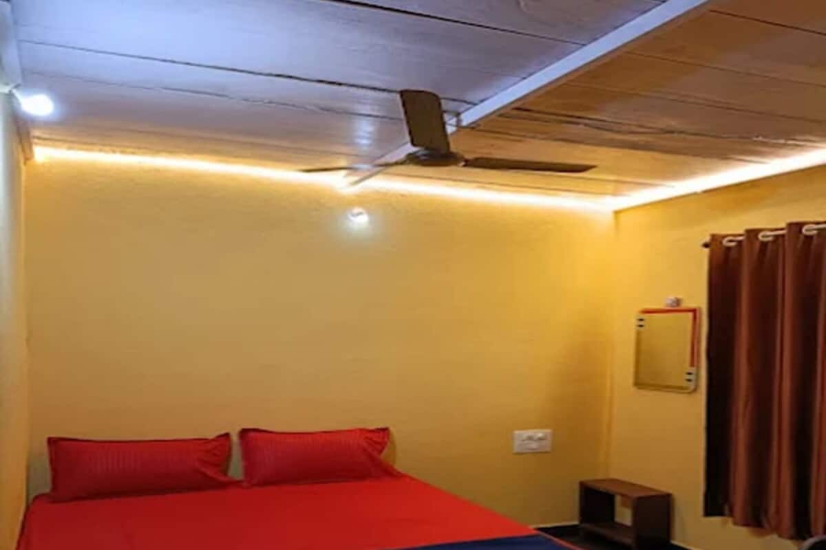 A room with a bed, a ceiling fan, a small table, and a mirror on the wall.