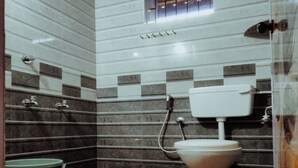 Een badkamer met een toilet, een emmer en een douche.