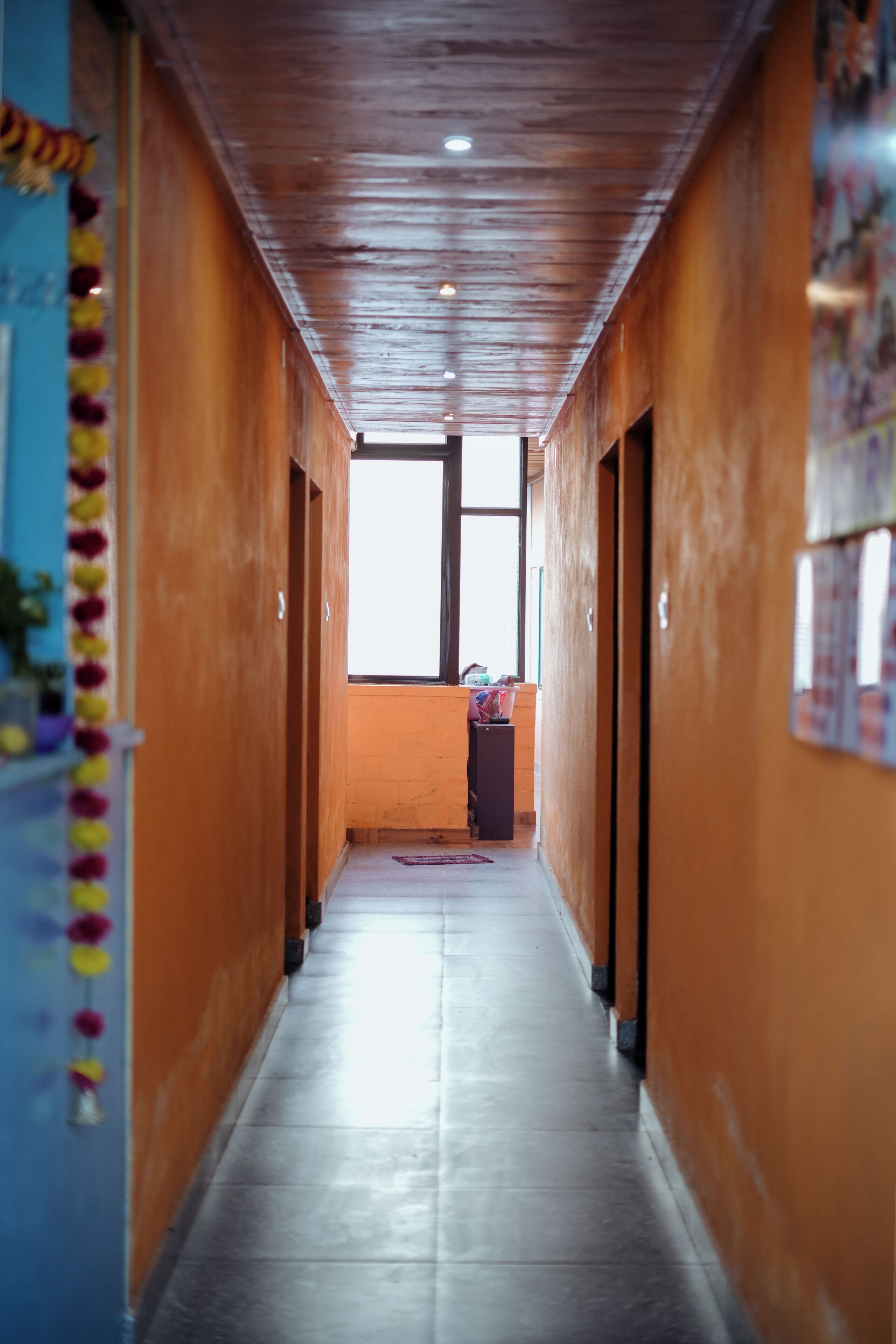 En hall med träpanel på väggarna och ett klinkergolv, som leder fram till ett fönster i slutet.