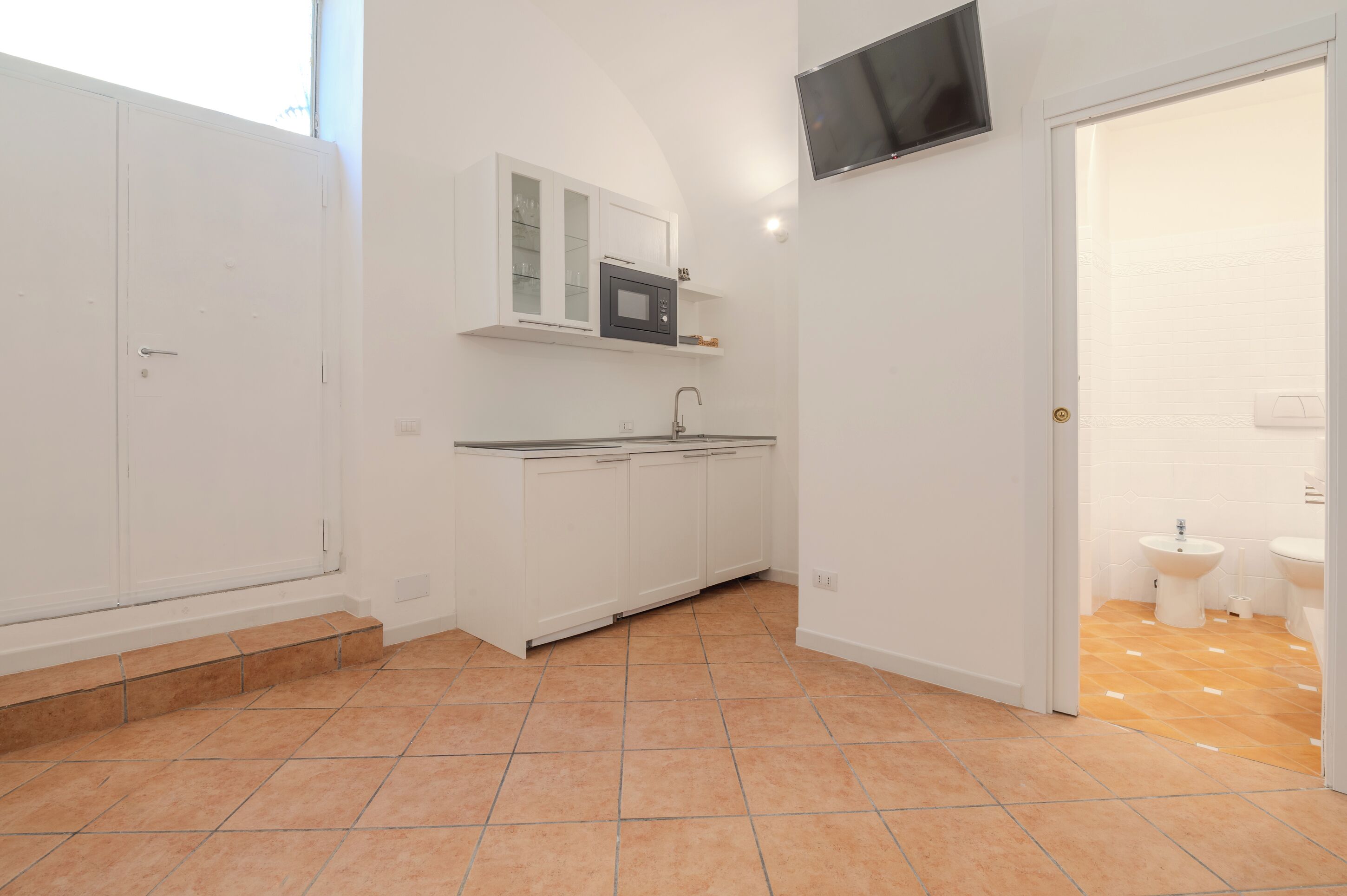 A kitchen with white cabinets, a microwave, and a sink.