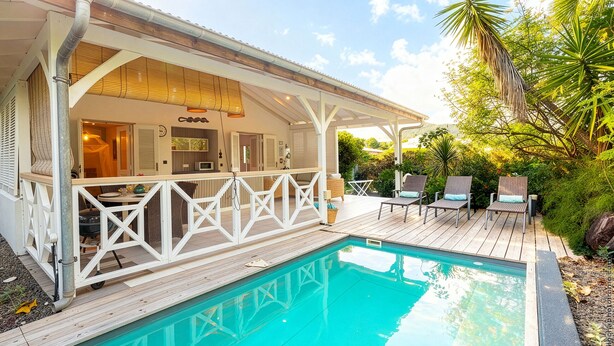 Un espace aménagé au bord de la piscine, avec une terrasse en bois, des chaises longues et un patio couvert.
