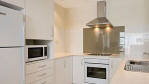 A modern kitchen with white cabinetry, a built-in microwave, an oven, and a stainless steel range hood. - 26Dec 2026 to 2Jan 2027 Beach House Accommodation - New Years (Coolangatta)