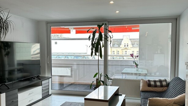 A modern living room with a large window, a flat-screen TV, a coffee table, and a sofa.