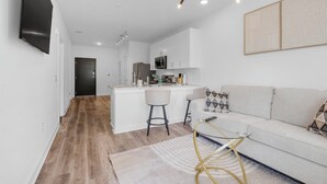 Una cucina moderna con mobili bianchi, un'isola centrale e sgabelli da bar.