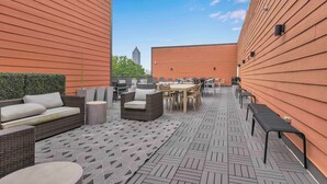Un'area patio all'aperto con mobili in rattan, un tappeto decorativo e vista sullo skyline della città.